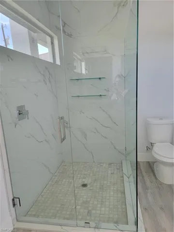 Bathroom with a shower with door, toilet, and hardwood / wood-style flooring