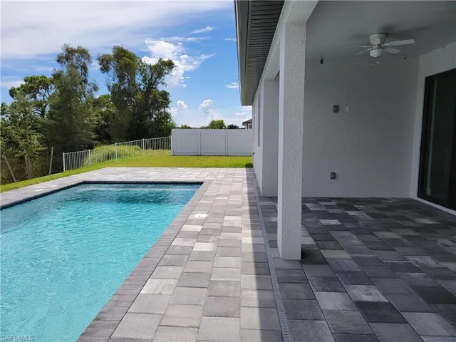 View of swimming pool with a patio, ceiling fan, and a lawn