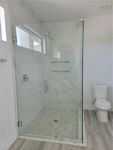 Bathroom with a shower with door, toilet, and hardwood / wood-style floors
