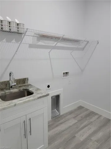 Washroom featuring sink, electric dryer hookup, light hardwood / wood-style flooring, and hookup for a washing machine