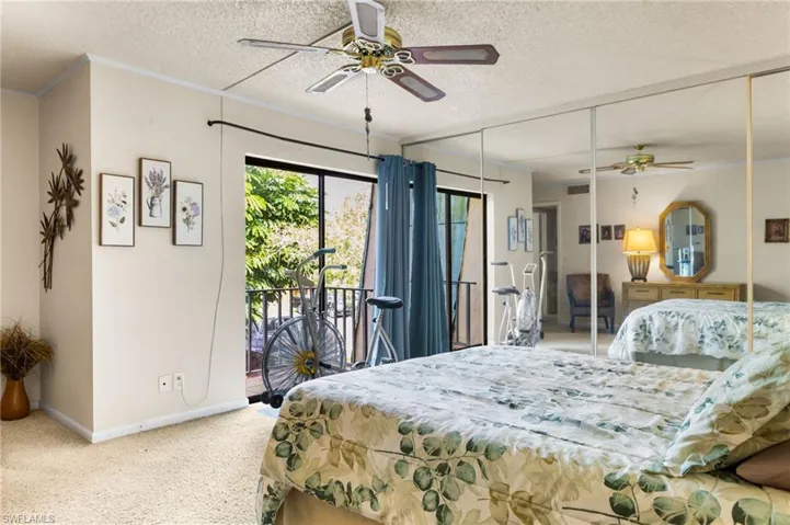 Primary bedroom with slider leading to balcony and overlooking patio.