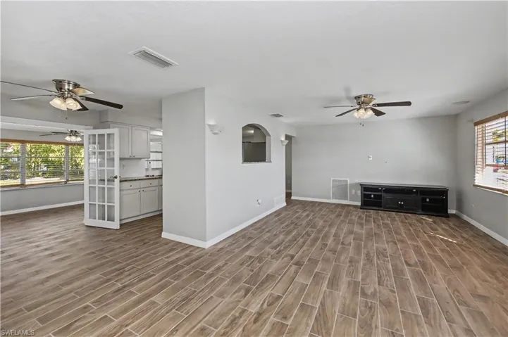 Unfurnished living room with ceiling fan, plenty of natural light, and wood finish floors