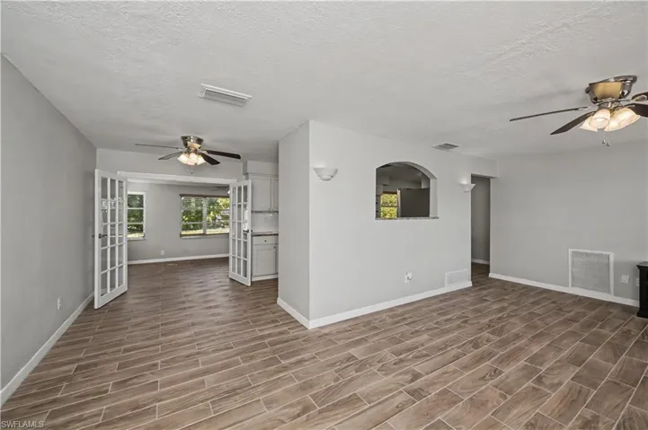 Unfurnished room featuring ceiling fan, a textured ceiling, wood finish floors, and french doors