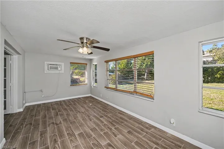 Unfurnished room with a textured ceiling, wood tiled floors, ceiling fan, and a wall mounted air conditioner