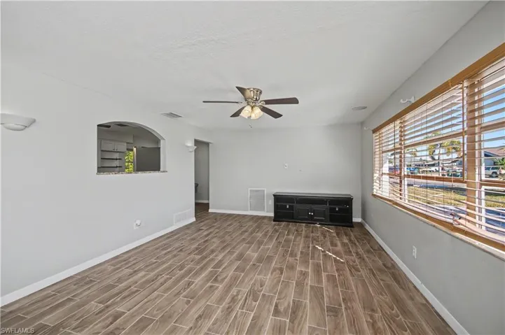 Unfurnished living room with wood finish floors, ceiling fan, and a textured ceiling