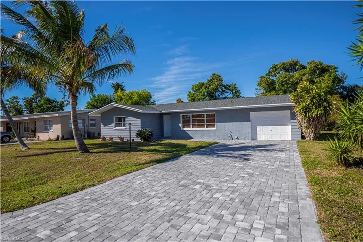 Ranch-style house with decorative driveway, an attached garage, a front lawn, and brick siding