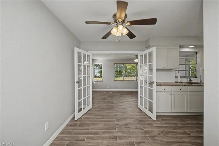 Kitchen featuring wood finish floors, white cabinets, glass insert cabinets, dark stone counters, and ceiling fan