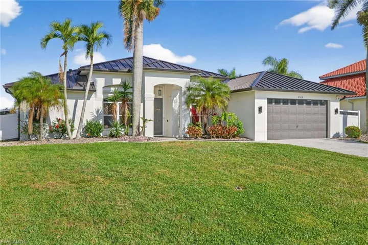Freshly painted exterior (2023) of this Mediterranean-style house with a new standing seam roof (2023), new gutters & soffits (2024), stucco siding, a garage, a front lawn, and pavered driveway - on a quarter acre