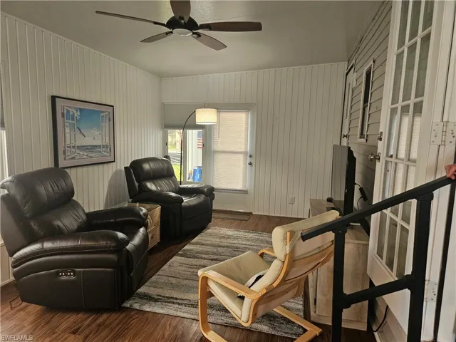 Living room featuring french doors, dark hardwood / wood-style floors, ceiling fan, and wooden walls