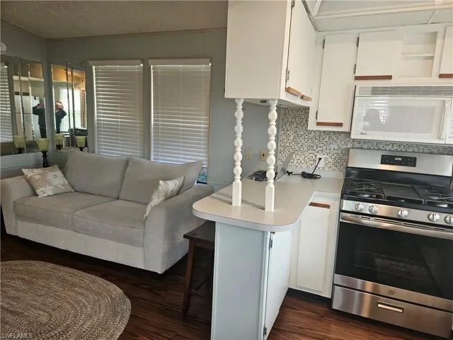 Kitchen featuring white cabinets, decorative backsplash, stainless steel range oven, kitchen peninsula, and a breakfast bar area