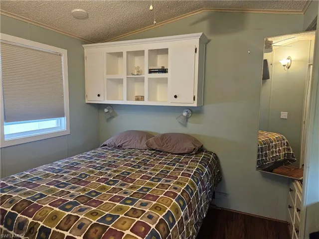 Bedroom with ornamental molding, a textured ceiling, and vaulted ceiling