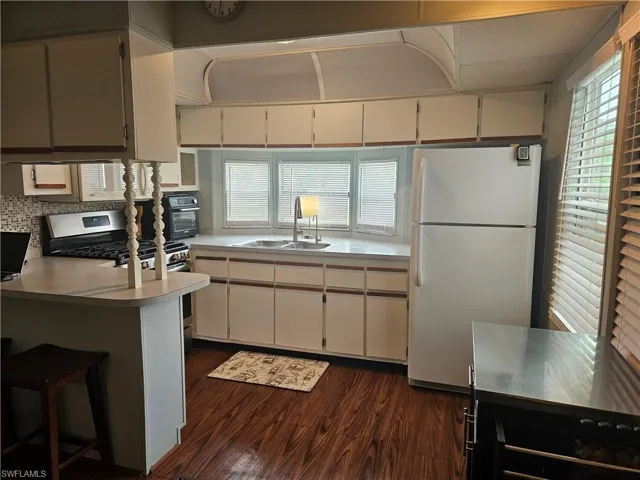 Kitchen featuring white cabinetry, sink, dark hardwood / wood-style floors, white refrigerator, and kitchen peninsula