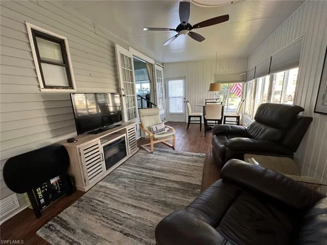 Living room with ceiling fan, dark hardwood / wood-style flooring, and wooden walls