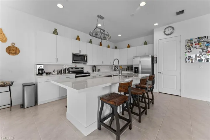 Kitchen with stainless steel appliances, a sink, visible vents, a kitchen breakfast bar, and light countertops