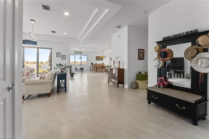 Living room featuring light tile patterned floors, a tray ceiling, visible vents, and recessed lighting