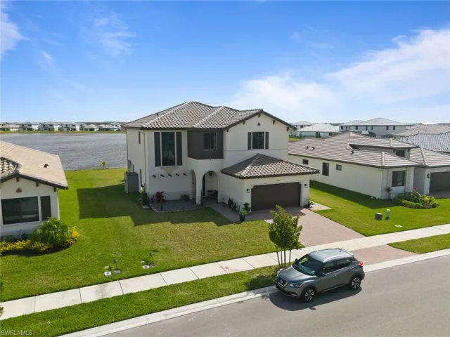View of front of property with a garage, a tiled roof, decorative driveway, a front lawn, and stucco siding