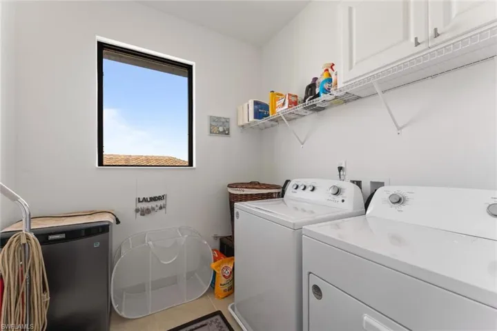 Laundry area with tile patterned flooring, cabinet space, and washer and dryer