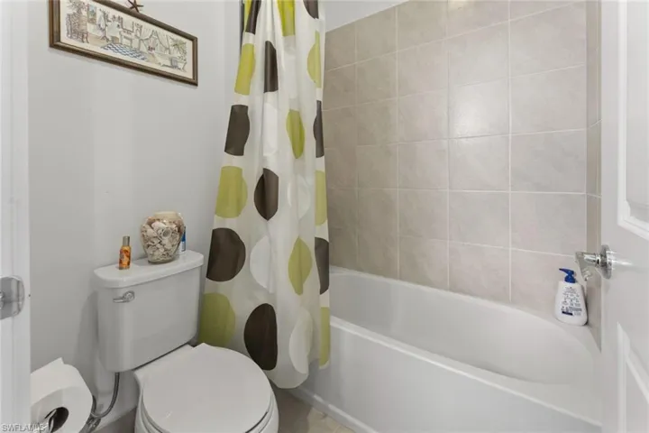 Bathroom with toilet and shower / bath combination with curtain