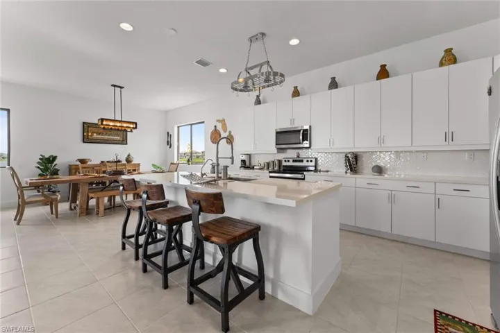 Kitchen featuring stainless steel appliances, light countertops, backsplash, and a breakfast bar area