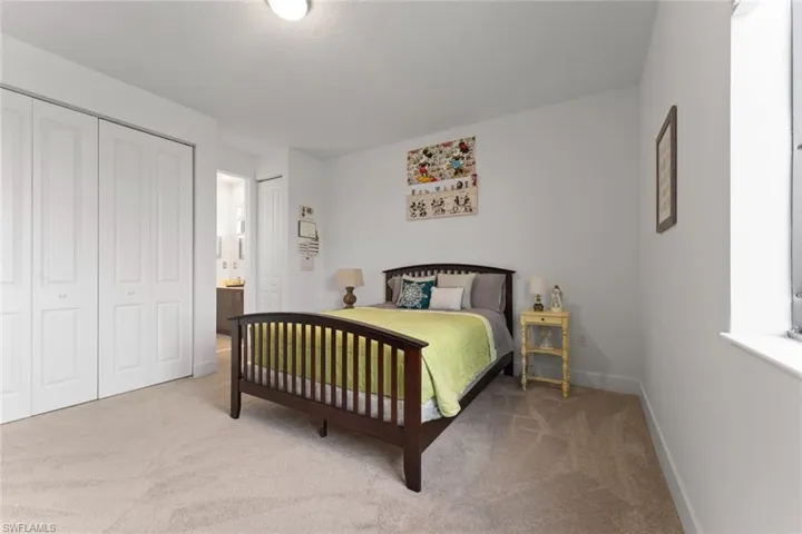 Bedroom with baseboards, two closets, and light colored carpet