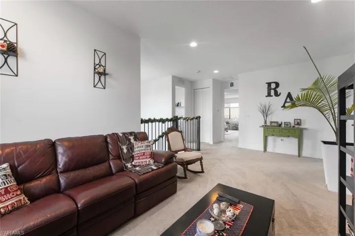 Living area with baseboards, recessed lighting, and light colored carpet
