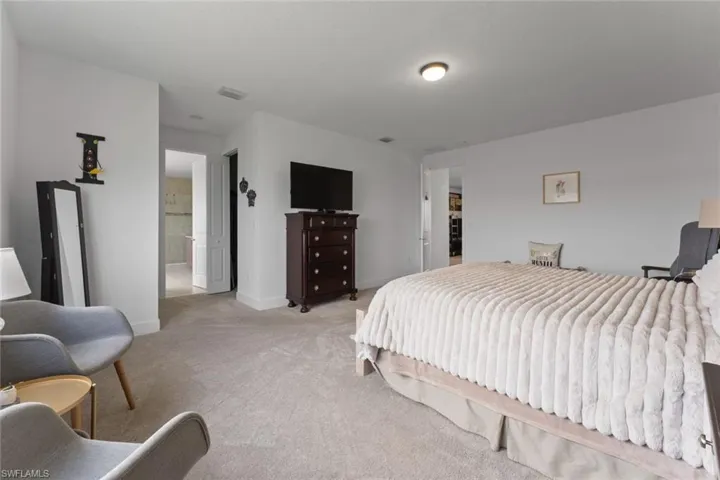 Bedroom with baseboards, visible vents, and light colored carpet