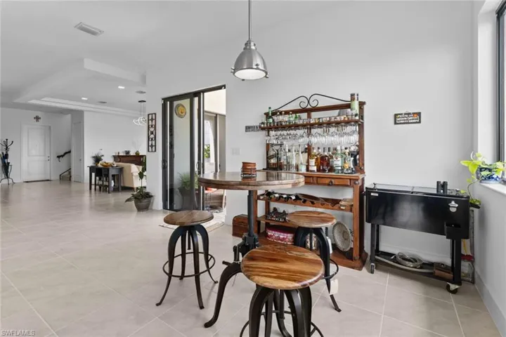 Bar with a dry bar, light tile patterned floors, visible vents, and recessed lighting