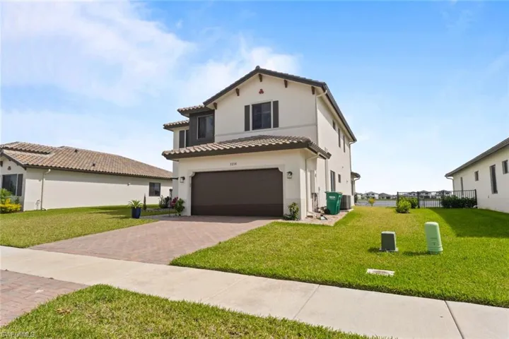Mediterranean / spanish house featuring a garage, a tile roof, decorative driveway, stucco siding, and a front yard