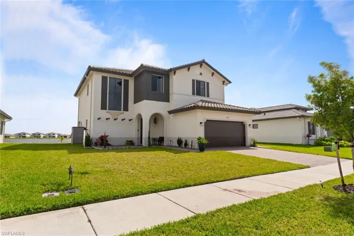 Mediterranean / spanish-style house with a garage, a tile roof, driveway, stucco siding, and a front yard