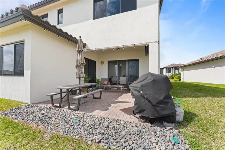 Back of house featuring a patio, a lawn, and stucco siding