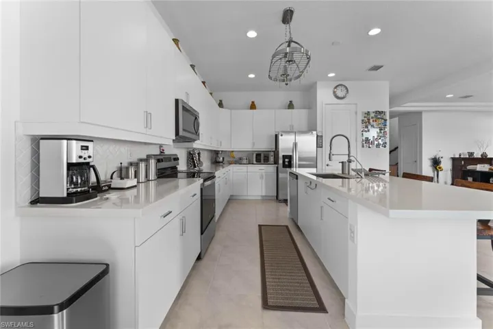 Kitchen with tasteful backsplash, appliances with stainless steel finishes, and light countertops