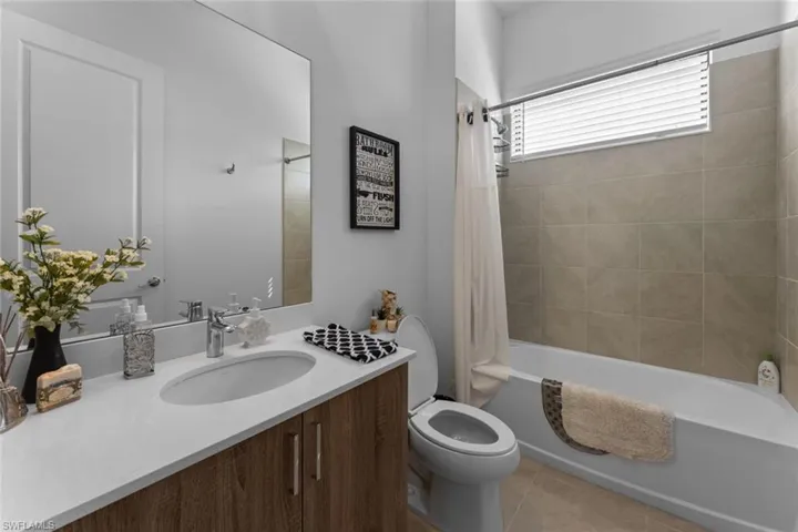 Bathroom with shower / tub combo, tile patterned flooring, vanity, and toilet