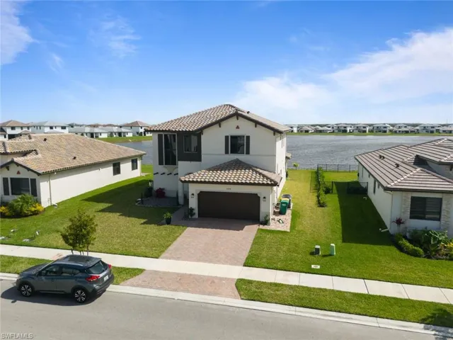 Mediterranean / spanish-style home with an attached garage, a tiled roof, decorative driveway, and a front yard