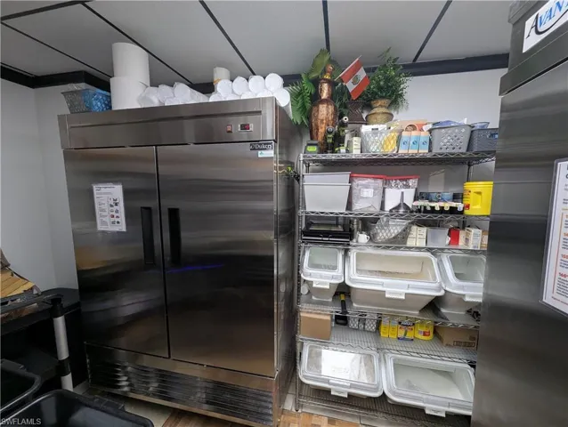 Stainless steel commercial refrigerator unit with dual doors, accompanied by metal shelving for organized storage