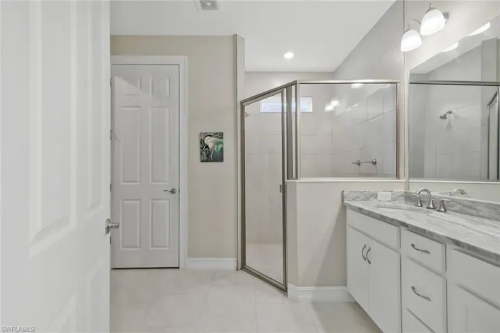 Full bath featuring a stall shower, vanity, and light tile patterned floors