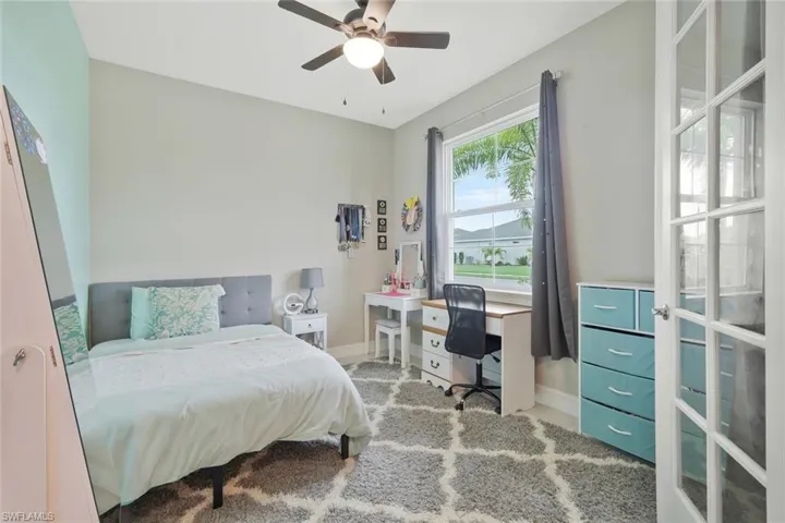 Bedroom featuring ceiling fan, light carpet, and a desk