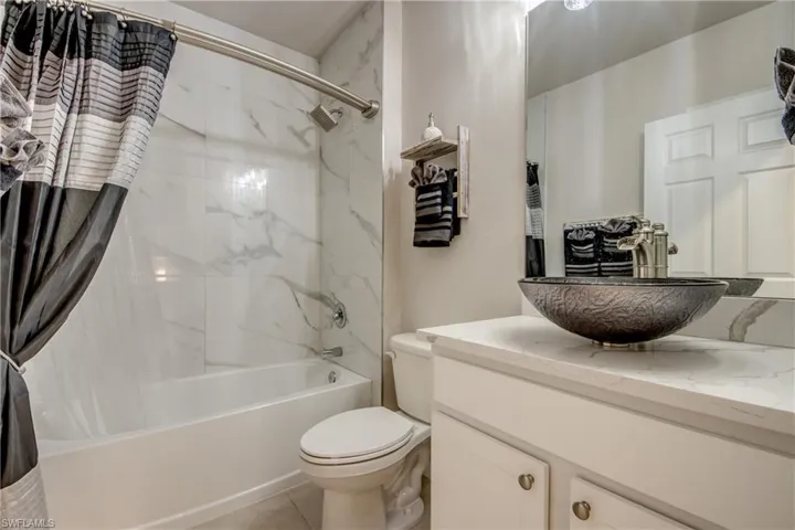 White vanity with cabinet storage, vessel sink, and a white countertop