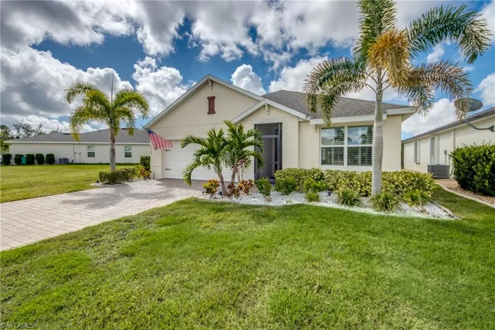 Paved driveway, attached two-car garage, screened entry, mature landscaping, and white window shutters