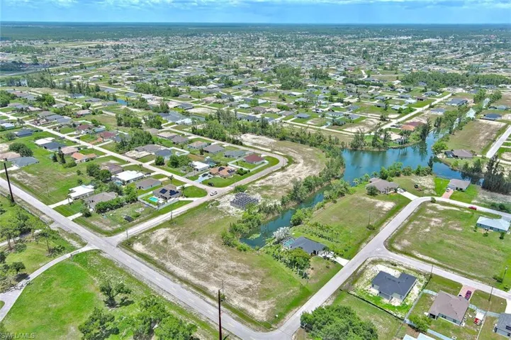 Aerial view of property and surrounding area featuring nearby suburban area and a large body of water