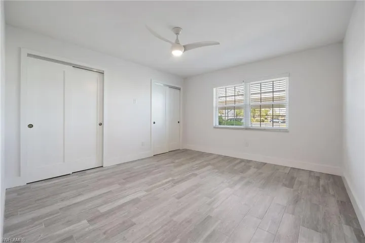 Guest bedroom featuring two closets , light wood-style flooring, baseboards, and a ceiling fan