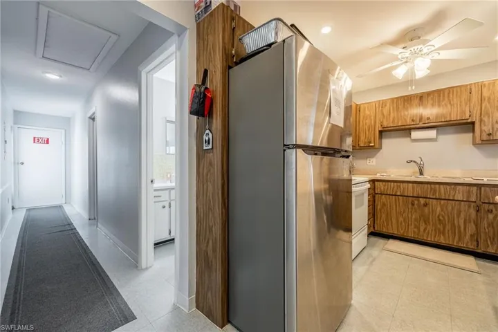 Clubhouse kitchen featuring freestanding refrigerator, electric range, light countertops, ceiling fan, and brown cabinetry