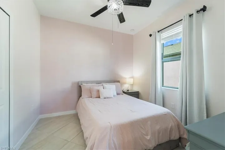 Room featuring neutral wall tones, a single window with blinds and drapes, tile flooring, and a ceiling fan with integrated lighting