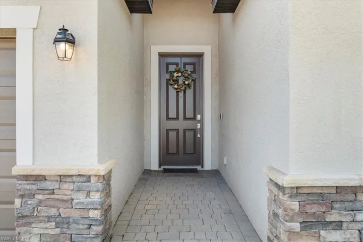Entryway featuring a paneled front door with decorative trim and a wrought iron lantern sconce