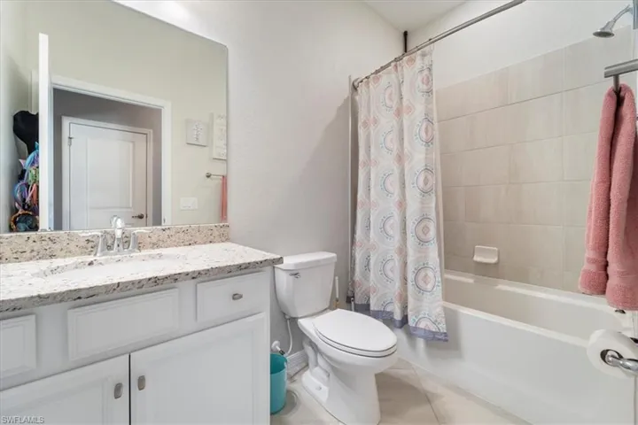 Full bathroom featuring a white vanity with a light-toned speckled countertop, an undermount sink, and a chrome faucet