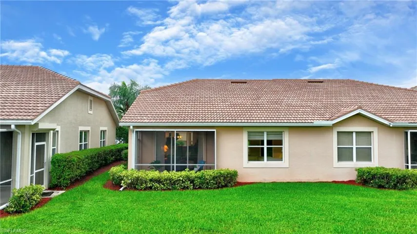 Back of house with a yard and lanai