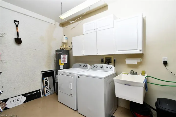 and dryer, sink, electric water heater, and cabinets
