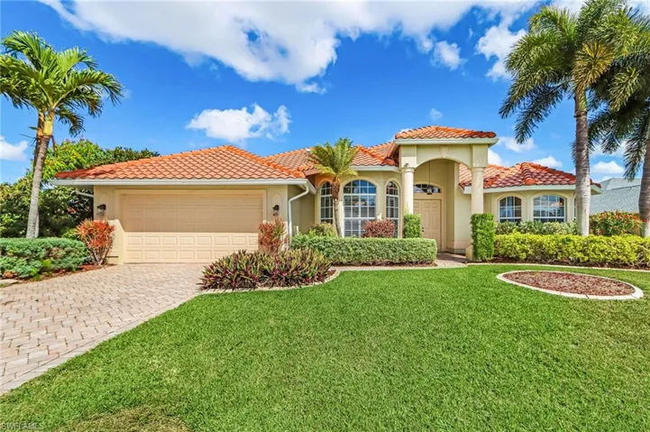 Mediterranean / spanish home with an attached garage, driveway, stucco siding, and a front lawn