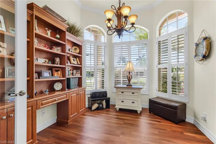 Office area with a chandelier, ornamental molding, dark wood finished floors, and built in study area