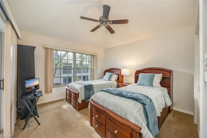 Bedroom featuring baseboards, light colored carpet, and vaulted ceiling