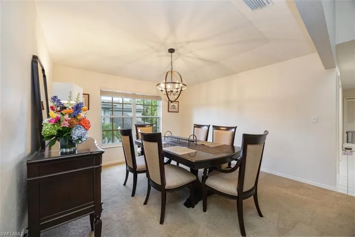 Dining area with light colored carpet, a notable chandelier, baseboards, and visible vents